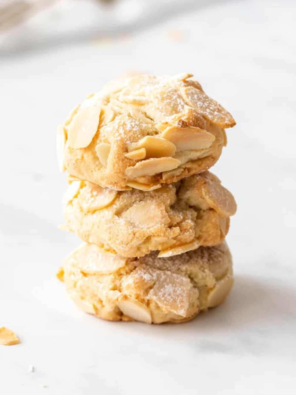 gluten free almond cookies in a stack on a white table.
