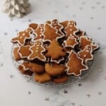 gingerbread cut out cookies in a bowl next to a white Christmas tree.