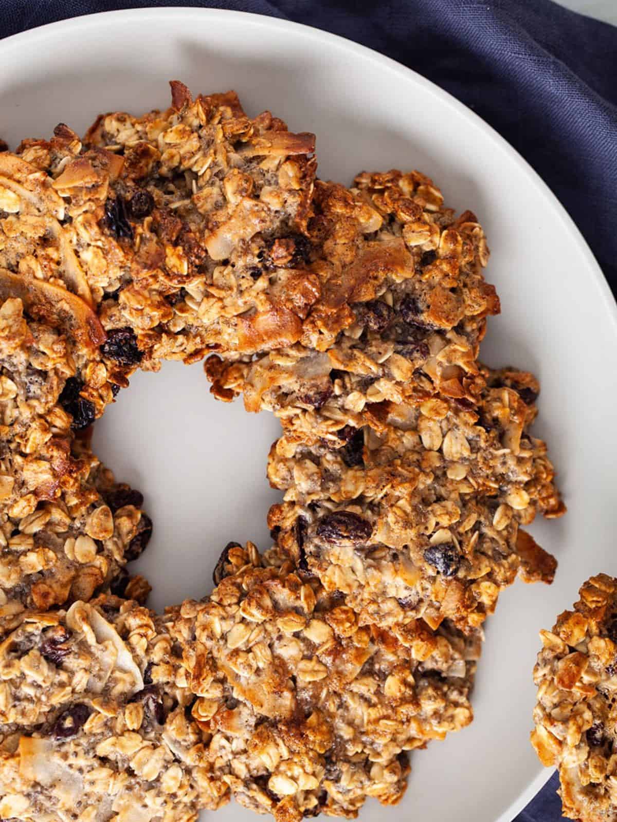 oatmeal raisin cookies on a white plate on a blue cloth.