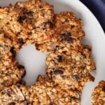 oatmeal raisin cookies on a white plate on a blue cloth.