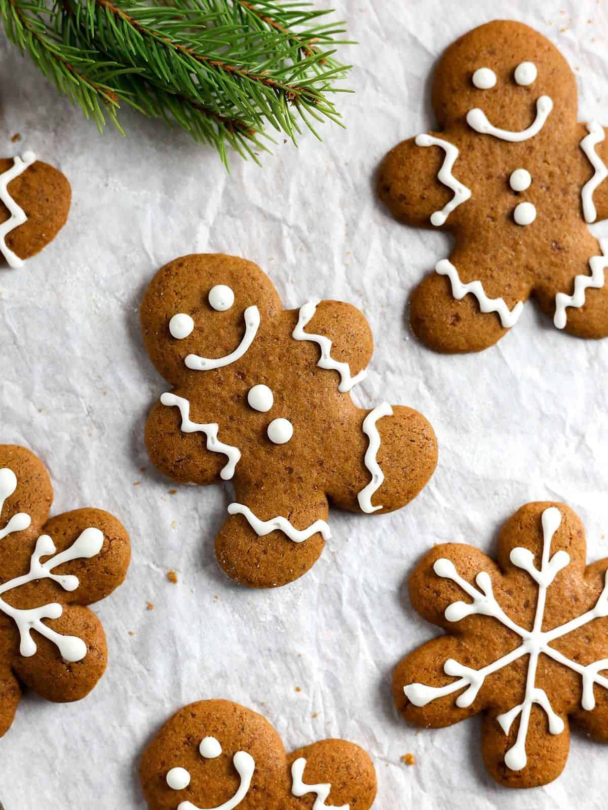 gingerbread men cookies on parchment paper next to green ferns.