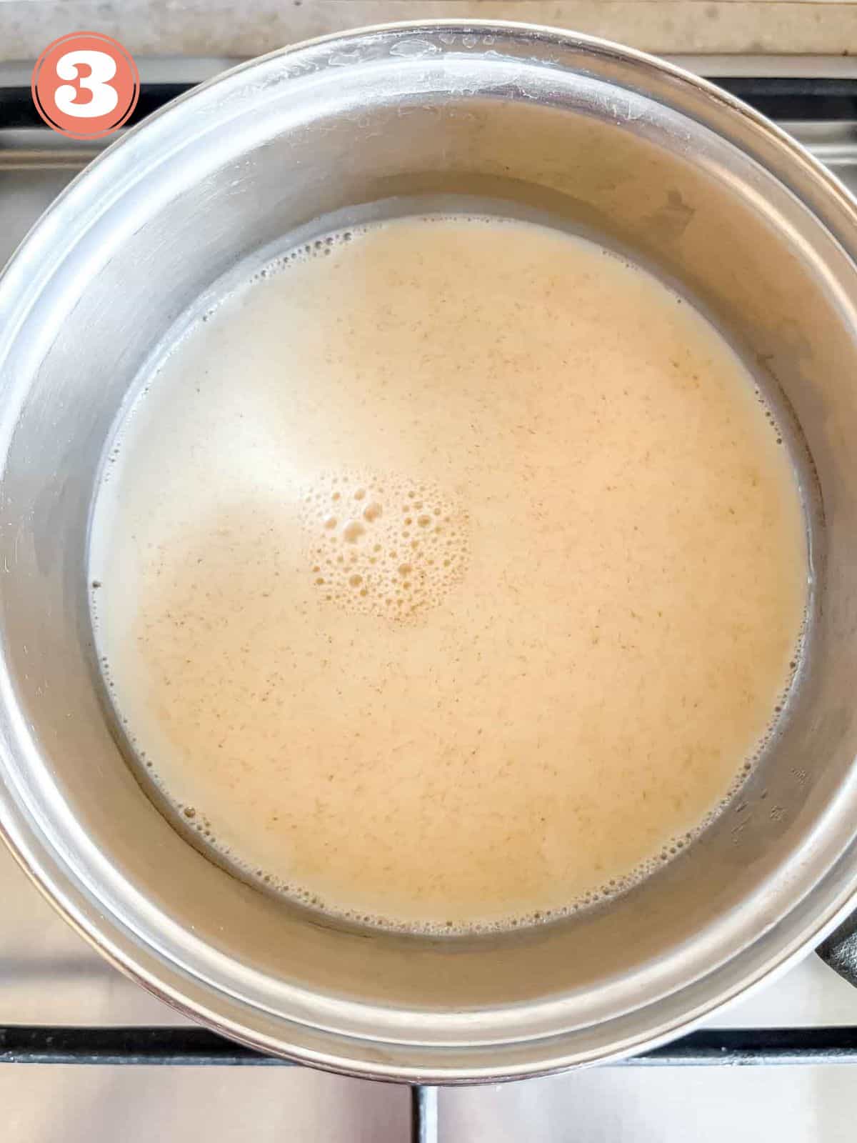 warm oat milk in a pot on a stove top labelled number three.