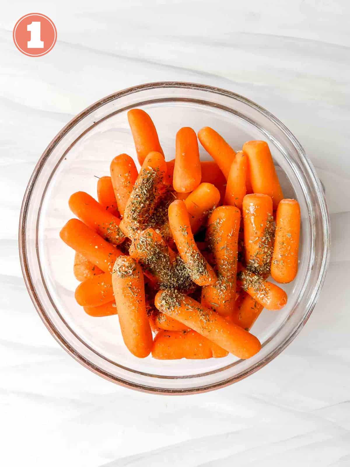 baby carrots with mixed herbs on top in a glass bowl labelled number one.