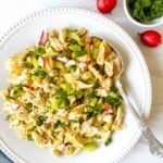 chicken salad without mayo on a white plate with a spoon next to parsley and radishes.
