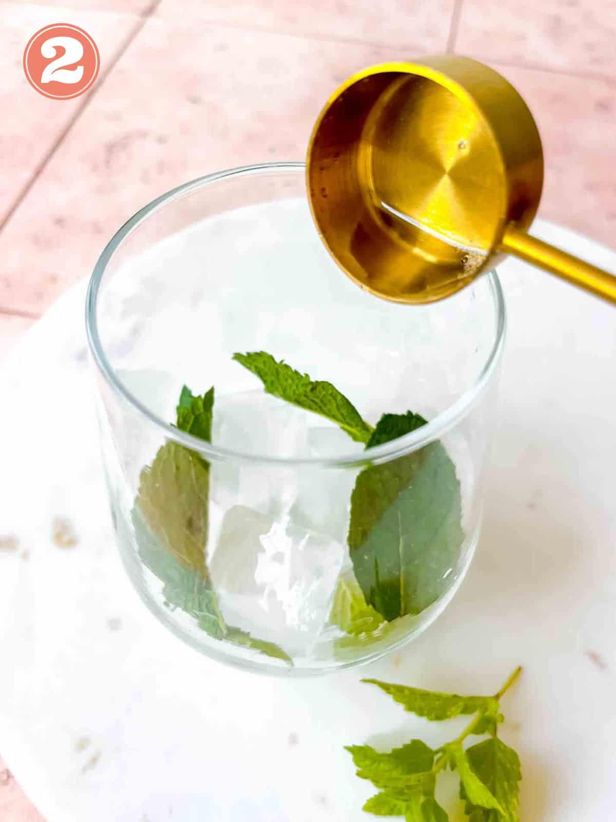 elderflower cordial being poured into a glass containing ice cubes and mint leaves labelled number two.
