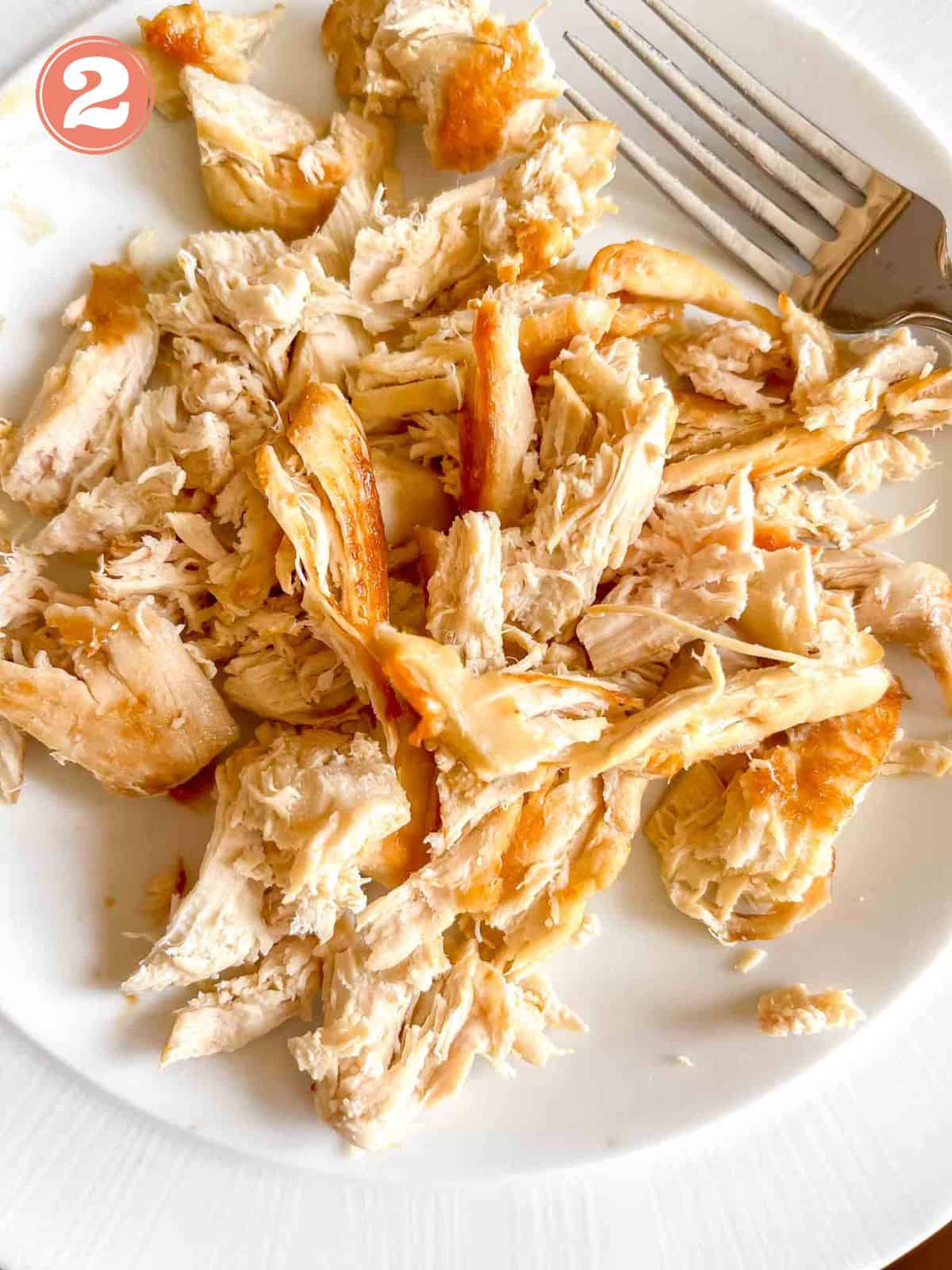 shredded chicken on a white plate with a fork labelled number two.