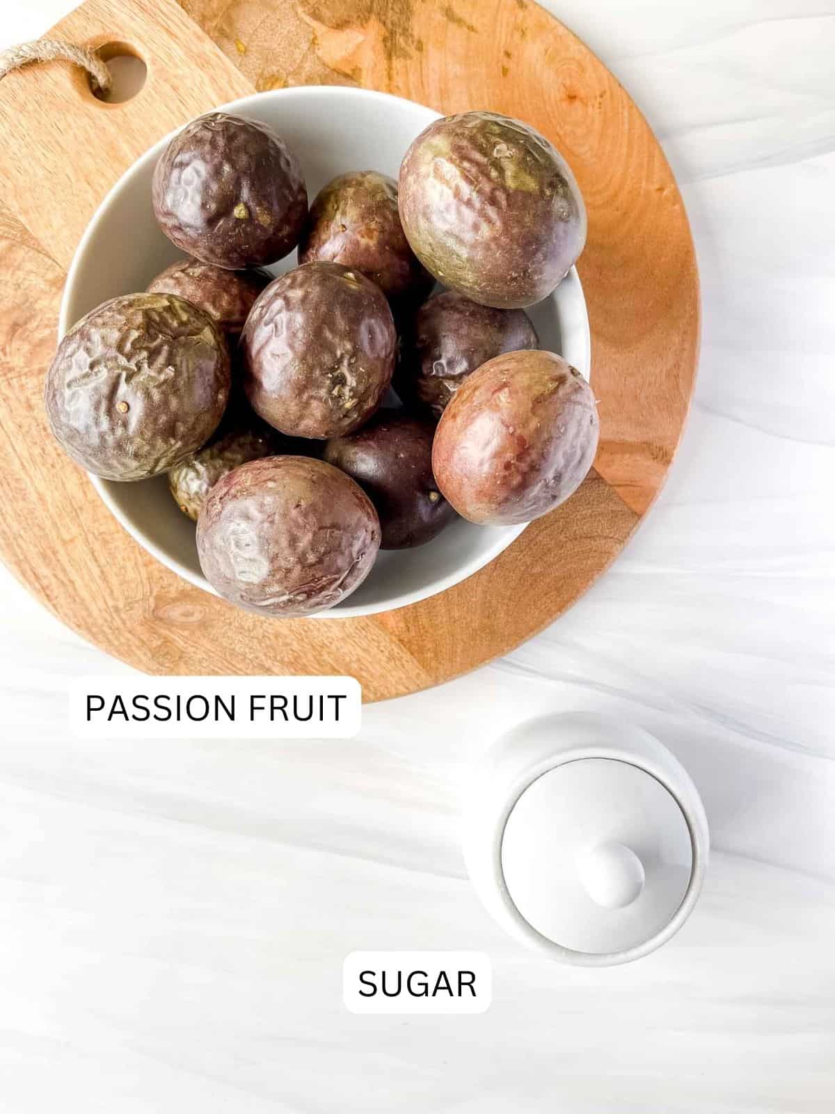 labelled passion fruit in a white bowl on a wooden board and sugar in a white sugar bowl.