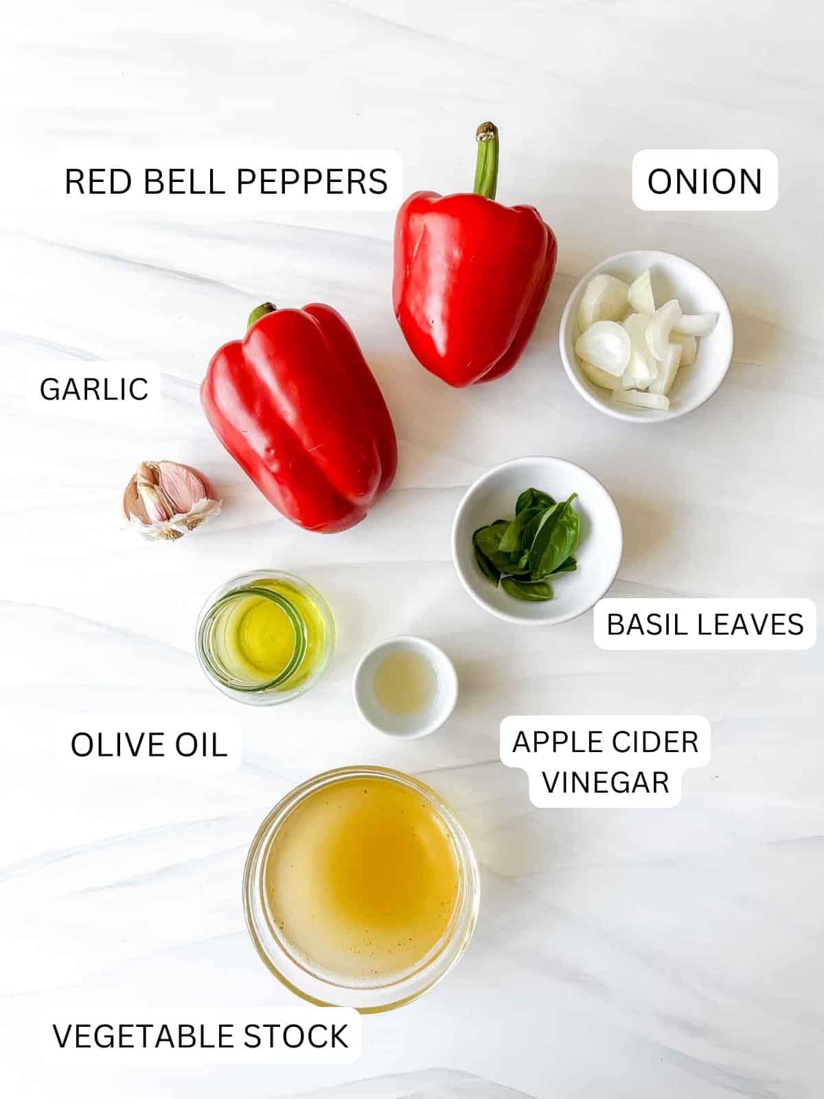 individually labelled ingredients to make red pepper coulis including red bell peppers, onion, basil leaves, garlic and olive oil.