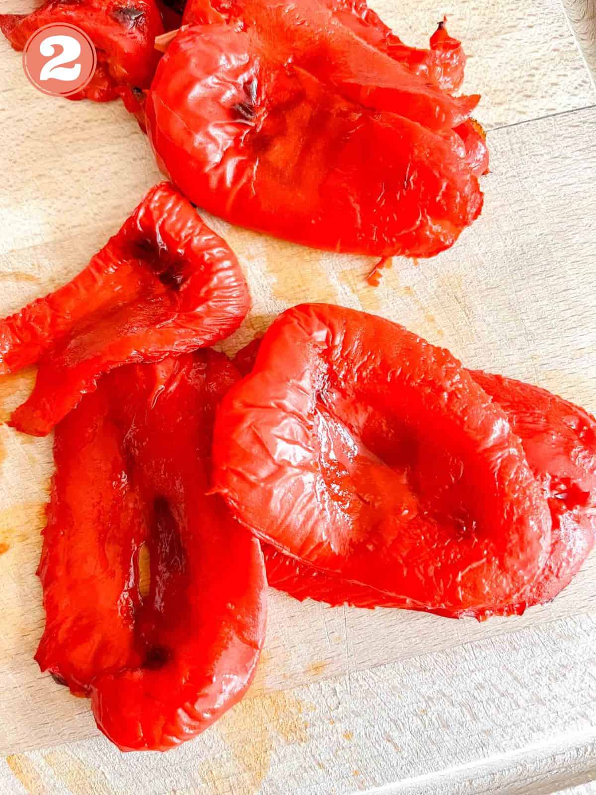 skinned red bell peppers on a wooden chopping board labelled number two.