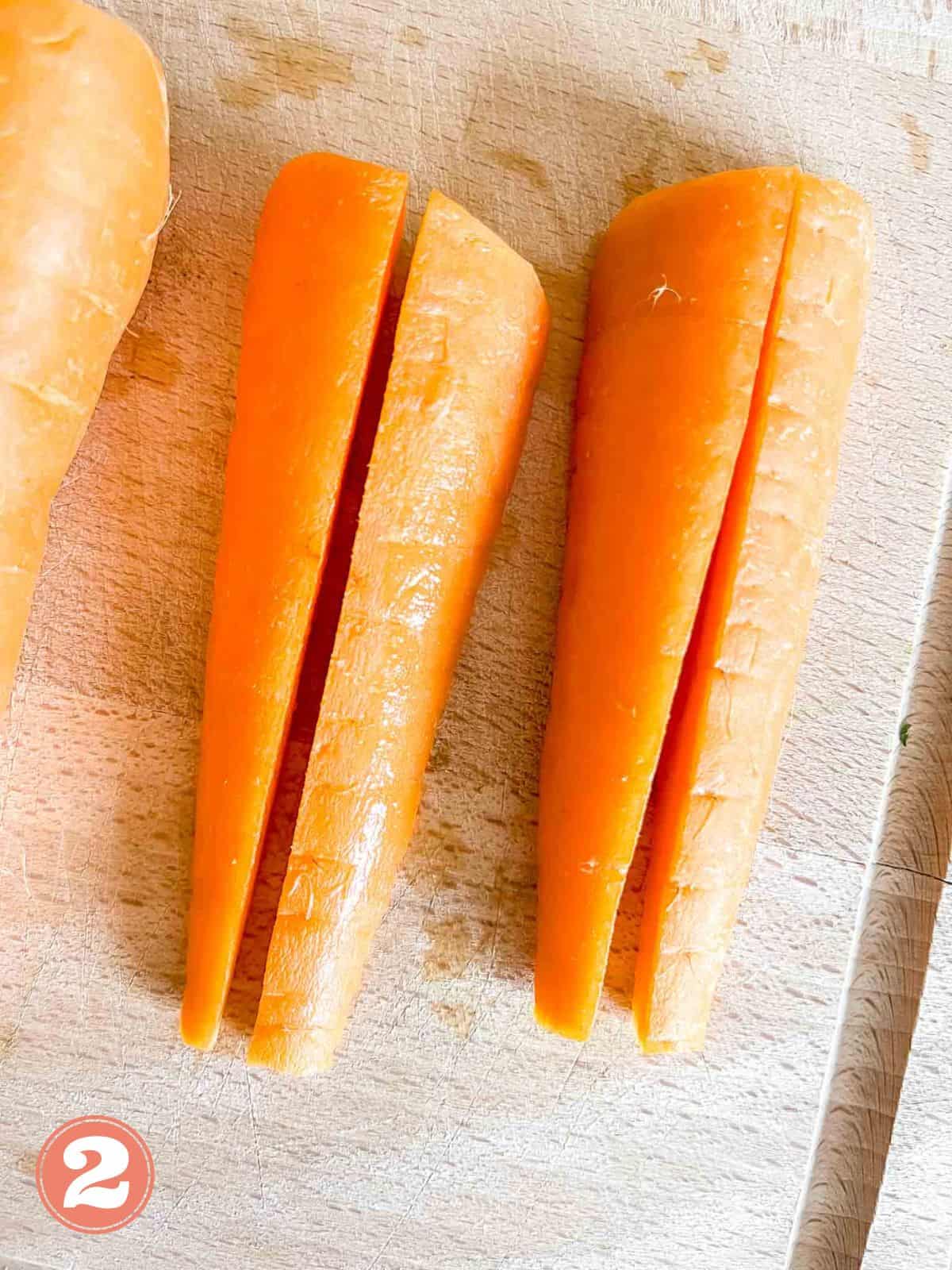 carrots sliced into halves on a wooden chopping board labelled number two.