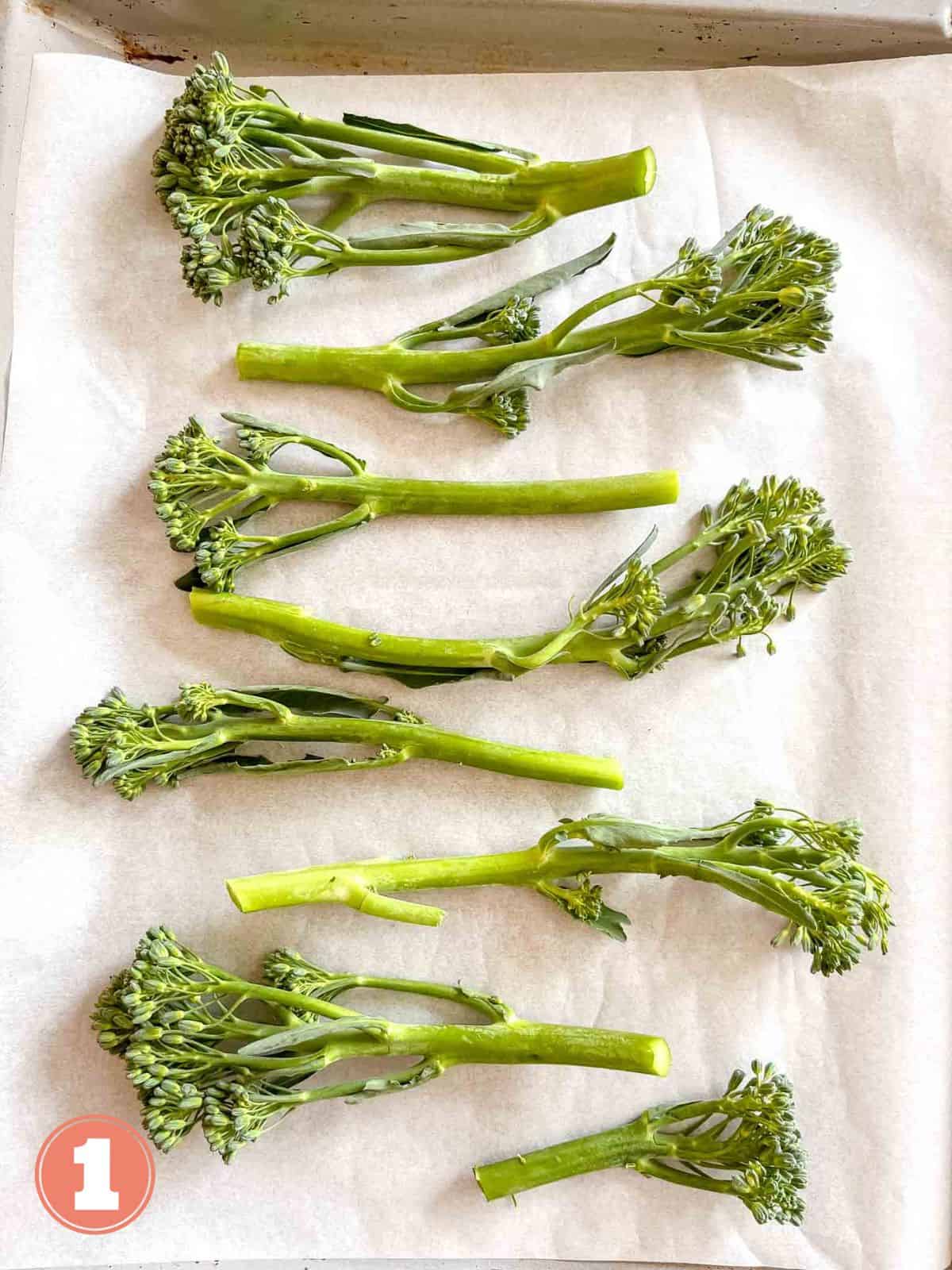tenderstem broccoli stems on parchment paper on a baking sheet labelled number one.