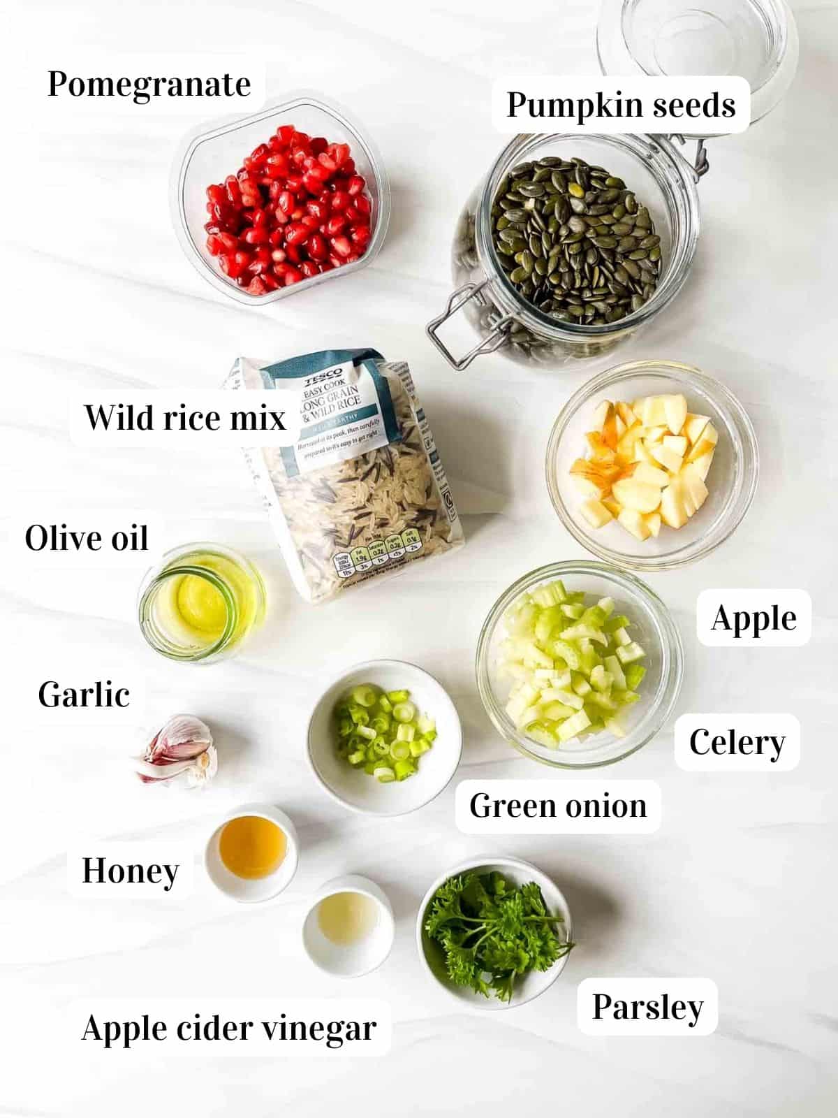 individually labelled ingredients to make summer wild rice salad including pomegranate seeds, apple, celery and pumpkin seeds.
