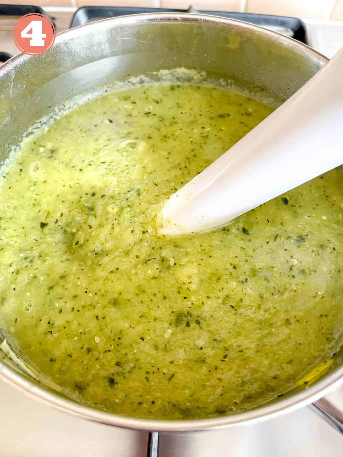 zucchini leek soup being blended with an immersion blender in a soup pot labelled number four.