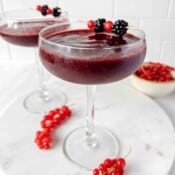 frozen berry mocktail in two glasses with a bowl of red currants in the background.