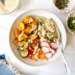 low histamine salad bowl with potatoes, quinoa, vegetables and herbs with a fork in it next to a blue cloth and small bowls of herbs and pumpkin seeds.