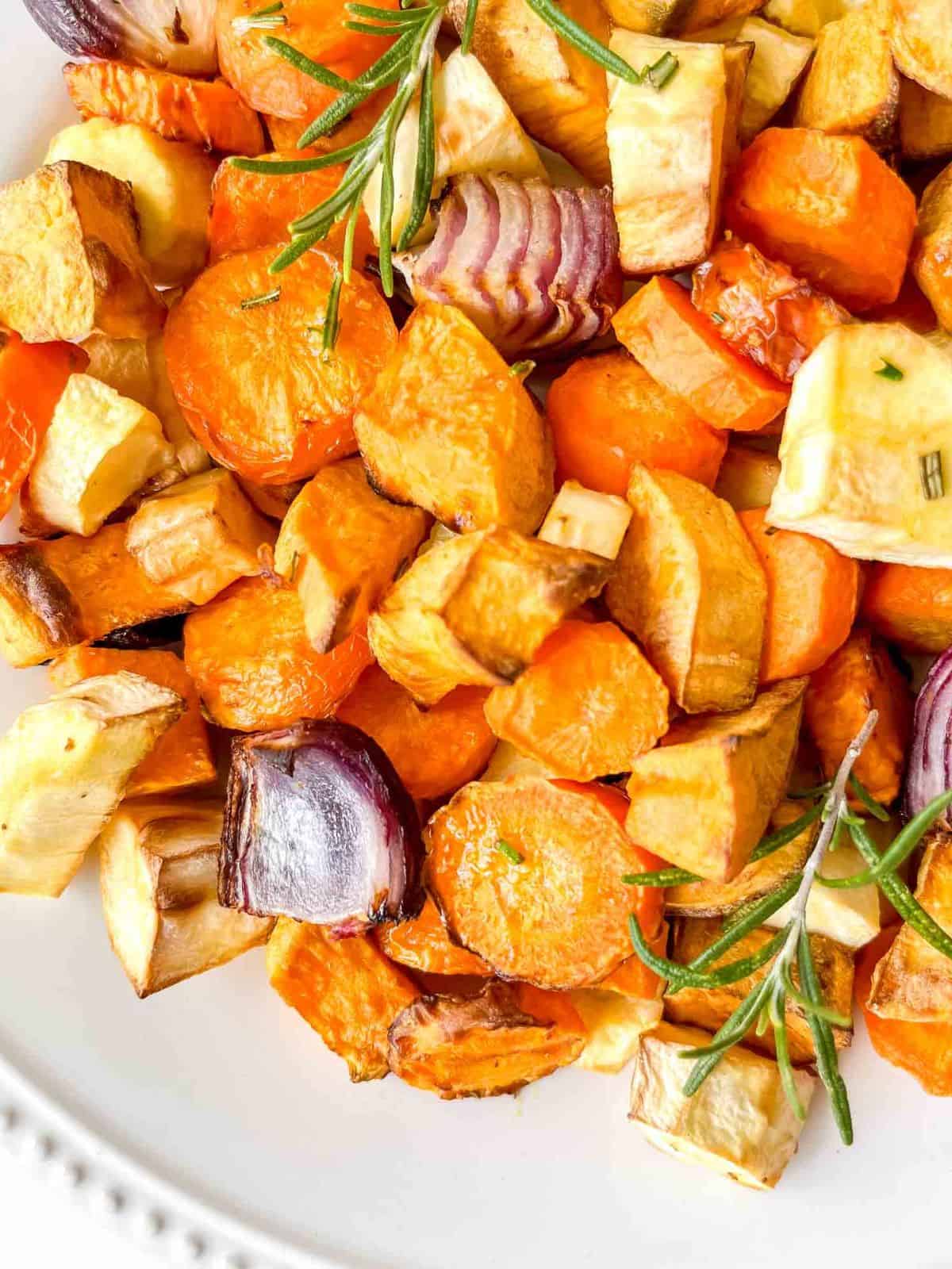 air fryer root vegetables with rosemary on a white plate.