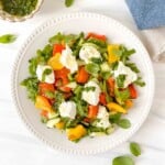 ricotta salad on a white plate next to a small bowl of herb dressing and a blue cloth.