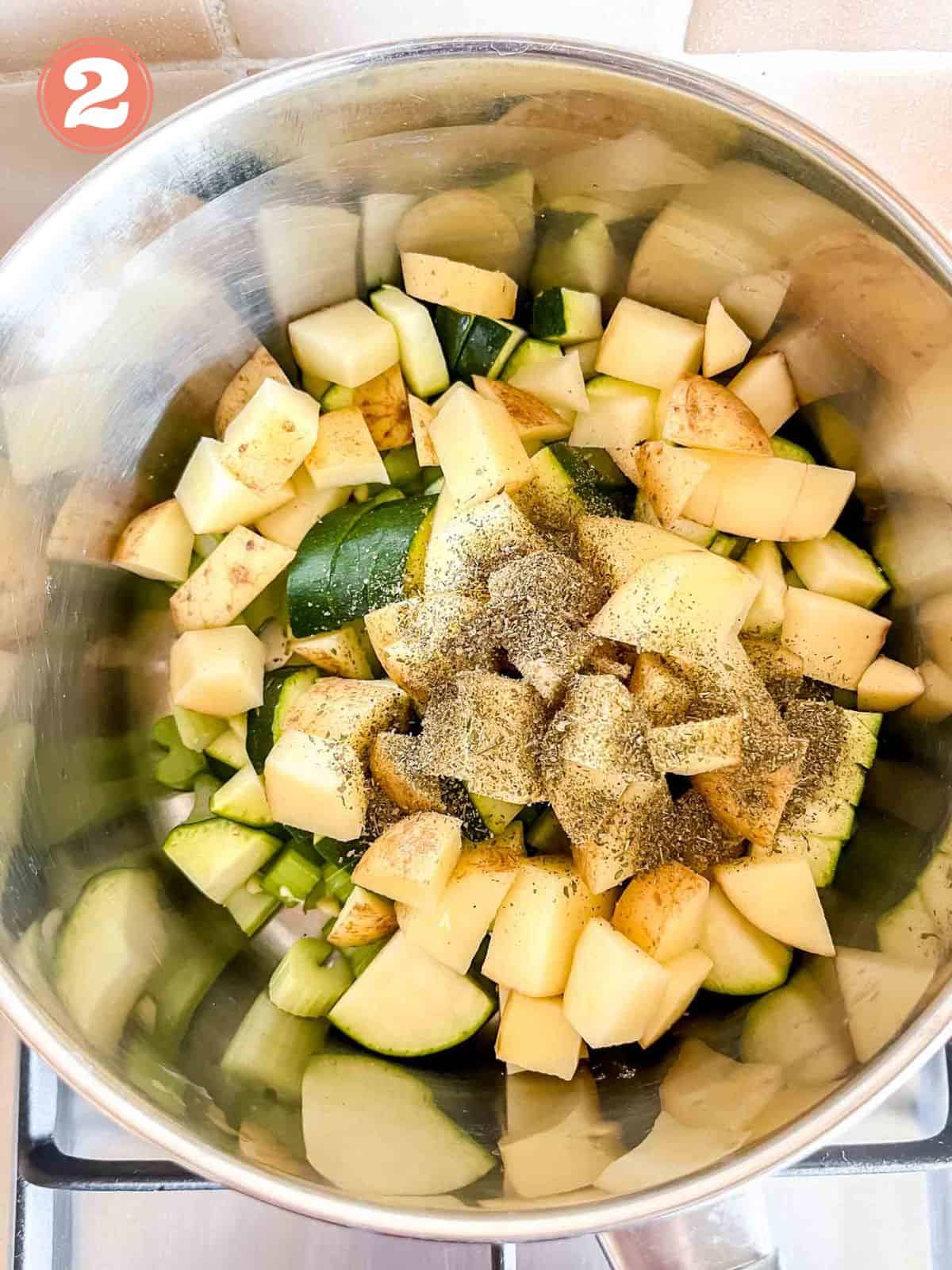 diced celery, zucchini, potato and dried herbs in a metal pot labelled number two.