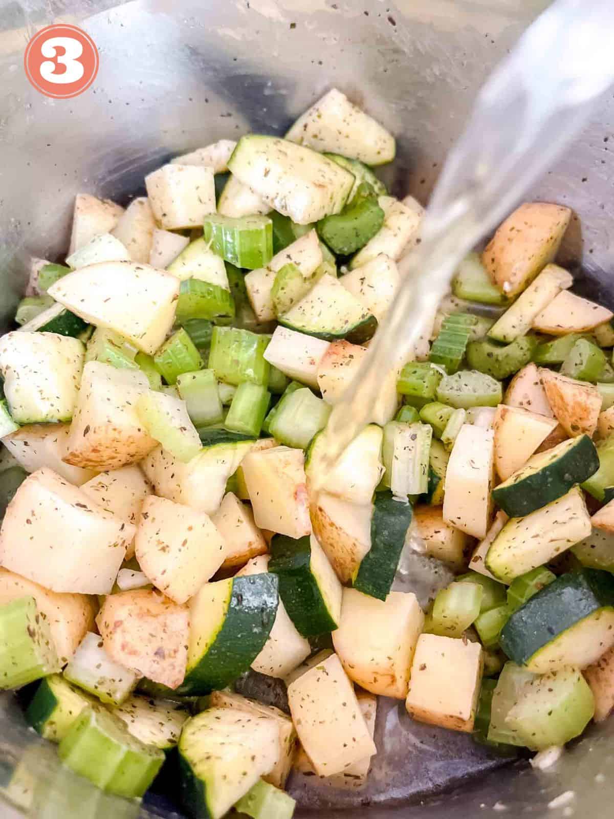 celery, potato and zucchini in a metal pot with vegetable stock being poured in labelled number three.