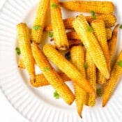cooked baby corn on a white plate.