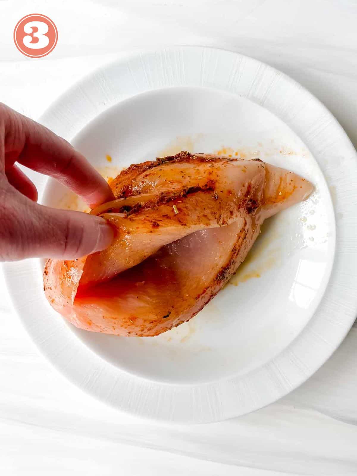 chicken breasts with a pocket sliced into it on a white plate labelled number three.