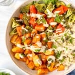 butternut squash quinoa bowl in a cream bowl drizzled with tahini dressing.