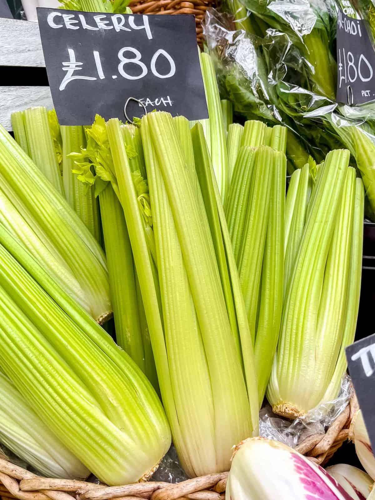 basket of bunches of celery with a sign stating celery one pound and eighty pence each.