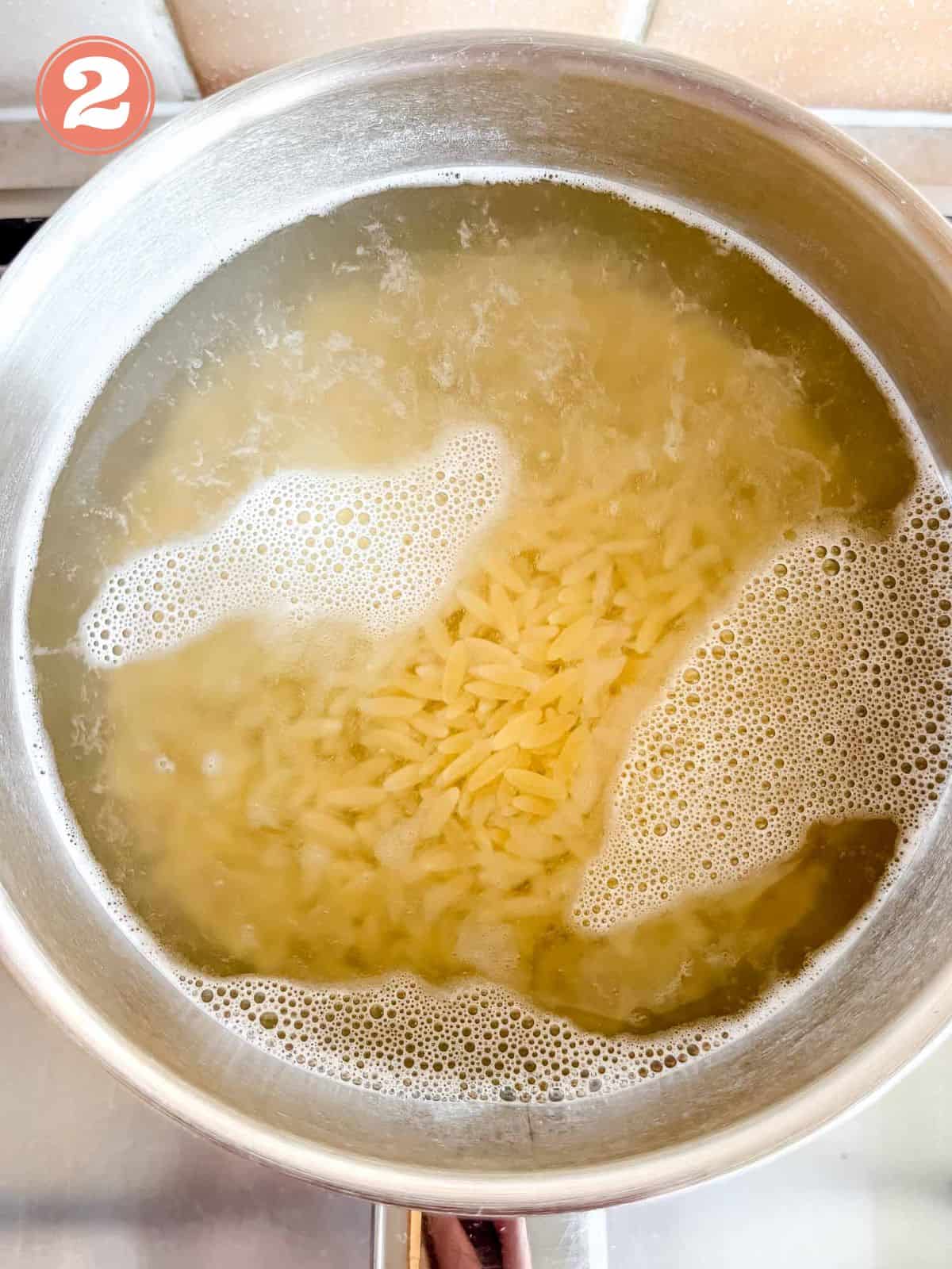 orzo pasta cooking in a pot on a stovetop labelled number two.