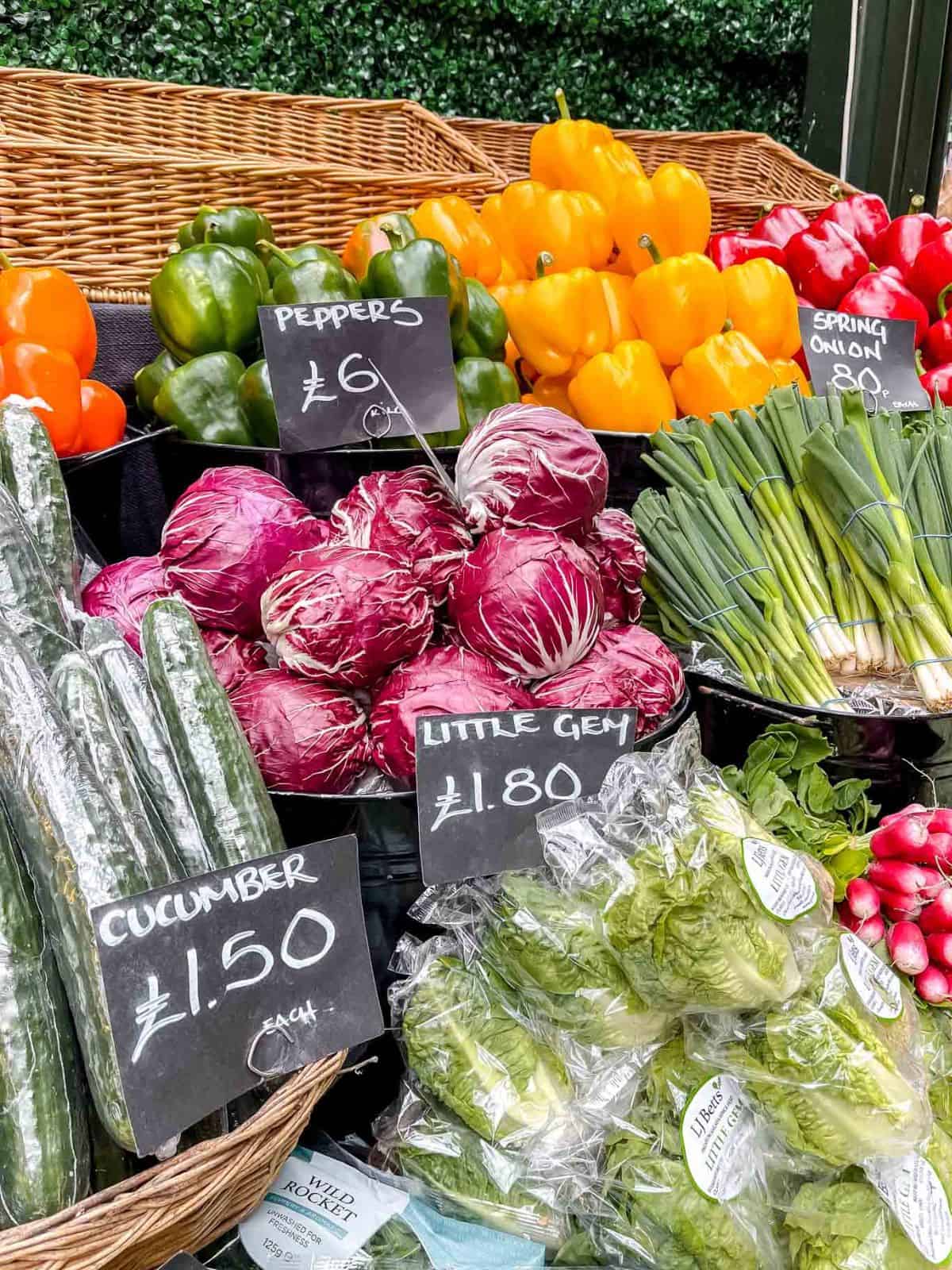 market stall with selections of vegetables including peppers, cucumbers and little gem lettuce.