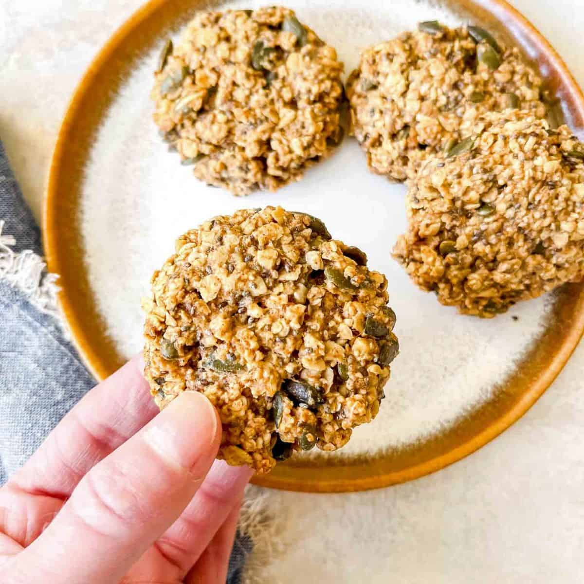 cookie being held over a plate of cookies.