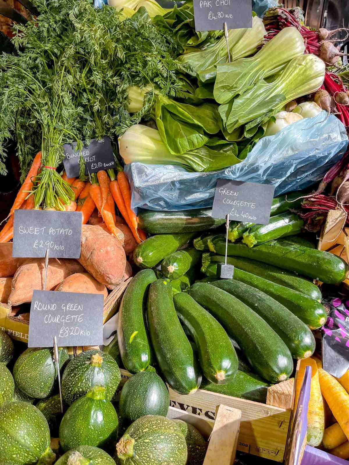 vegetables at a farmers market including zucchini, carrots and sweet potatoes.
