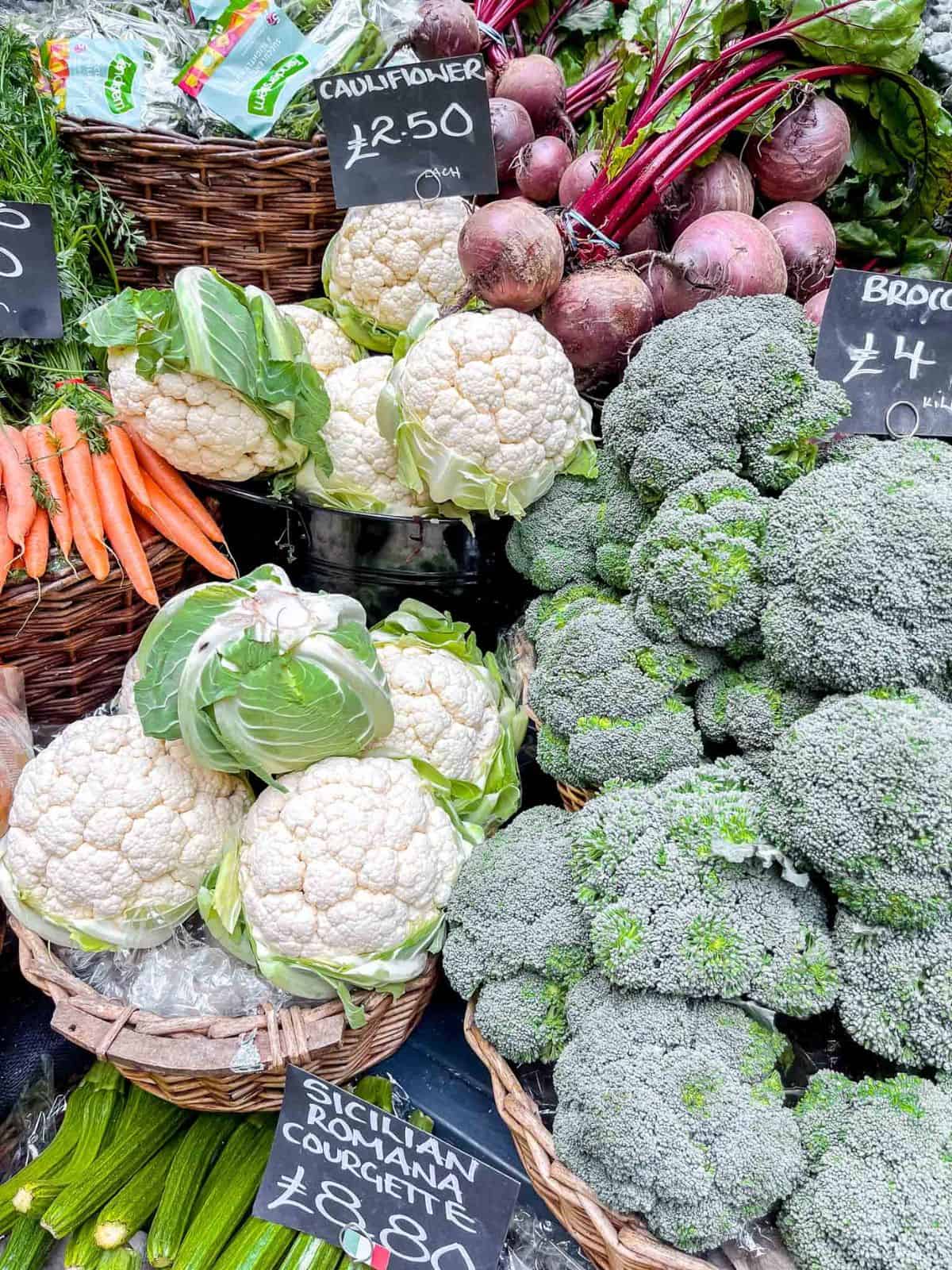 cauliflowers, broccoli and beets at a farmers market stall.