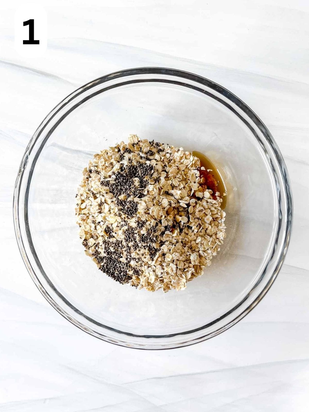 oats, chia seeds and maple syrup in a glass bowl labelled number one.