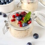 overnight oats with oat milk in two glass mason jars topped with berries.