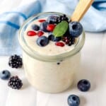 blended overnight oats in a glass jar topped with blueberries, blackberries and pomegranate seeds.