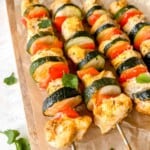 oven baked coconut paprika chicken skewers on a wooden board.