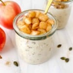 applesauce overnight oats in two glass jars next to red apples.