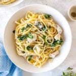 chicken ricotta pasta in a white bowl next to a blue cloth and fresh herbs.