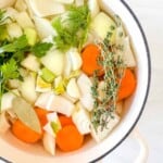 diced vegetables, parsley, thyme and garlic in water to make vegetable stock in a pot.