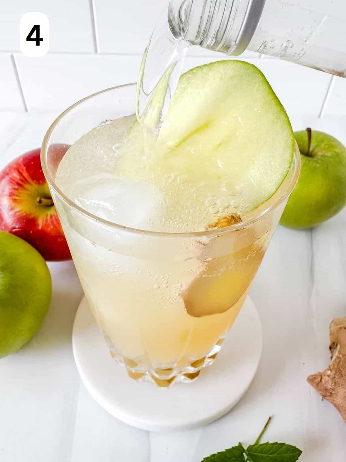 sparkling water being poured onto apple juice and ice in a glass labelled number four.