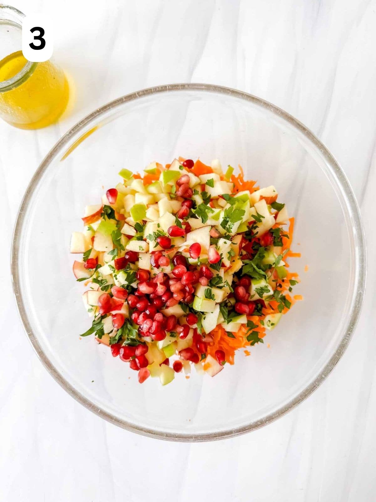 grated carrot, diced apples, pomegranate and parsley in a glass bowl labelled number three.
