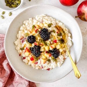 cottage cheese and apple bowl topped with diced apples, blackberries and seeds.