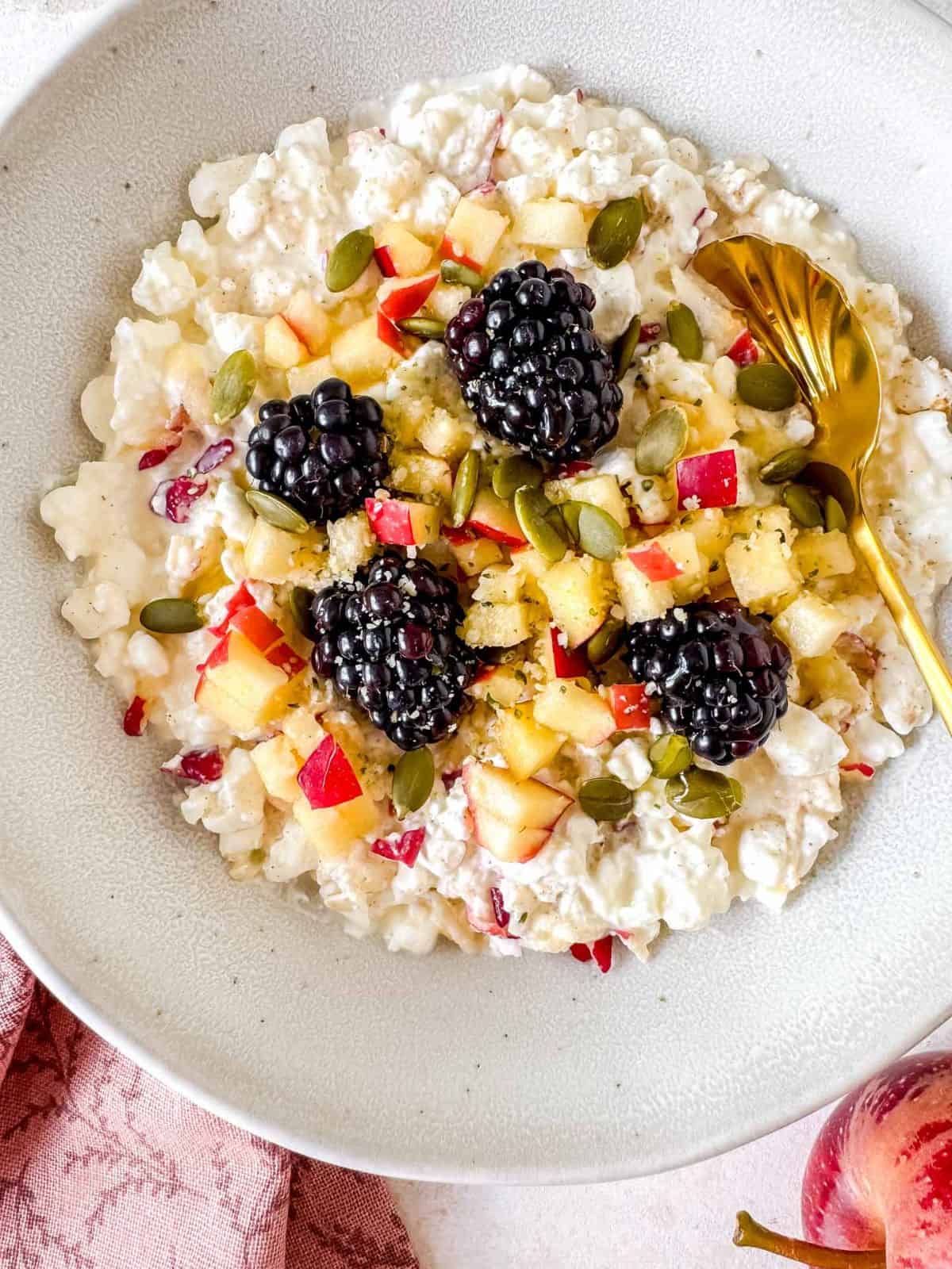 cottage cheese and apple bowl garnished with blackberries, pumpkin seeds and hemp seeds.
