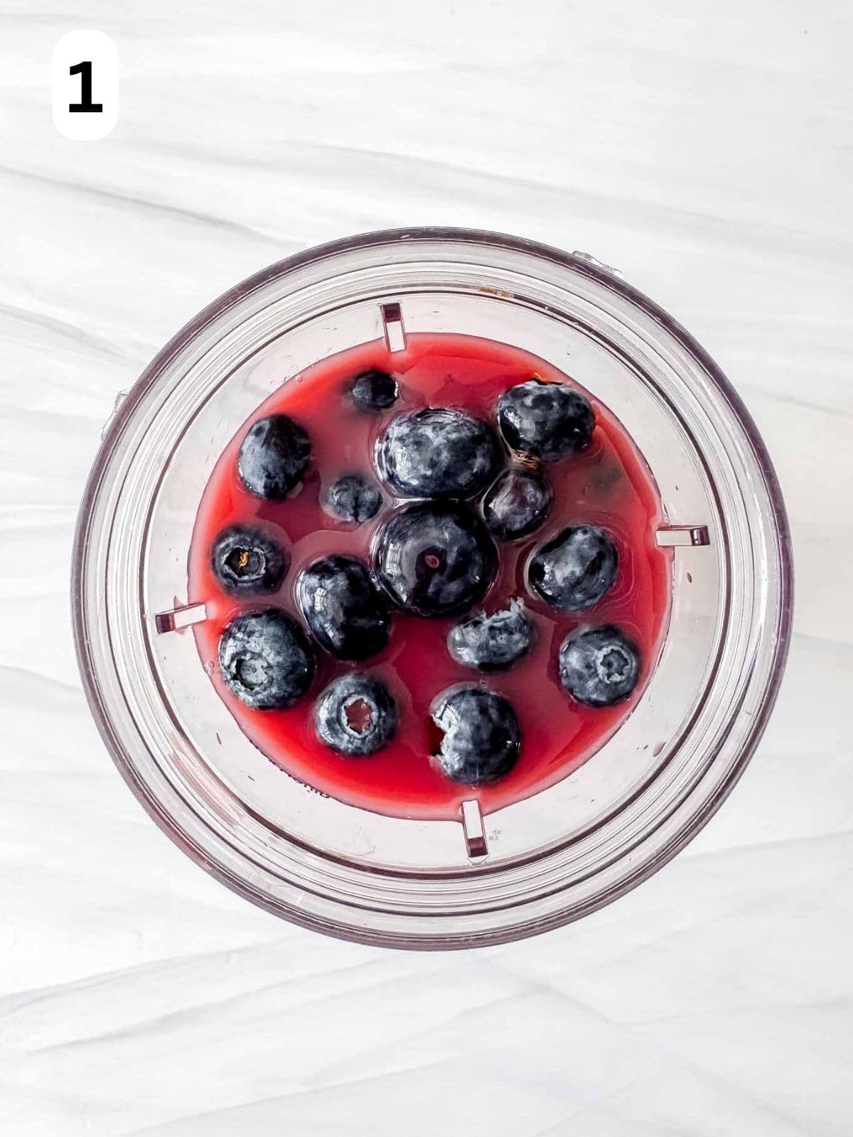 blueberries and pomegranate juice in a blender cup labelled number one.