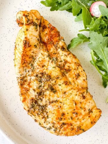 air fryer thin chicken breast on a plate with arugula.