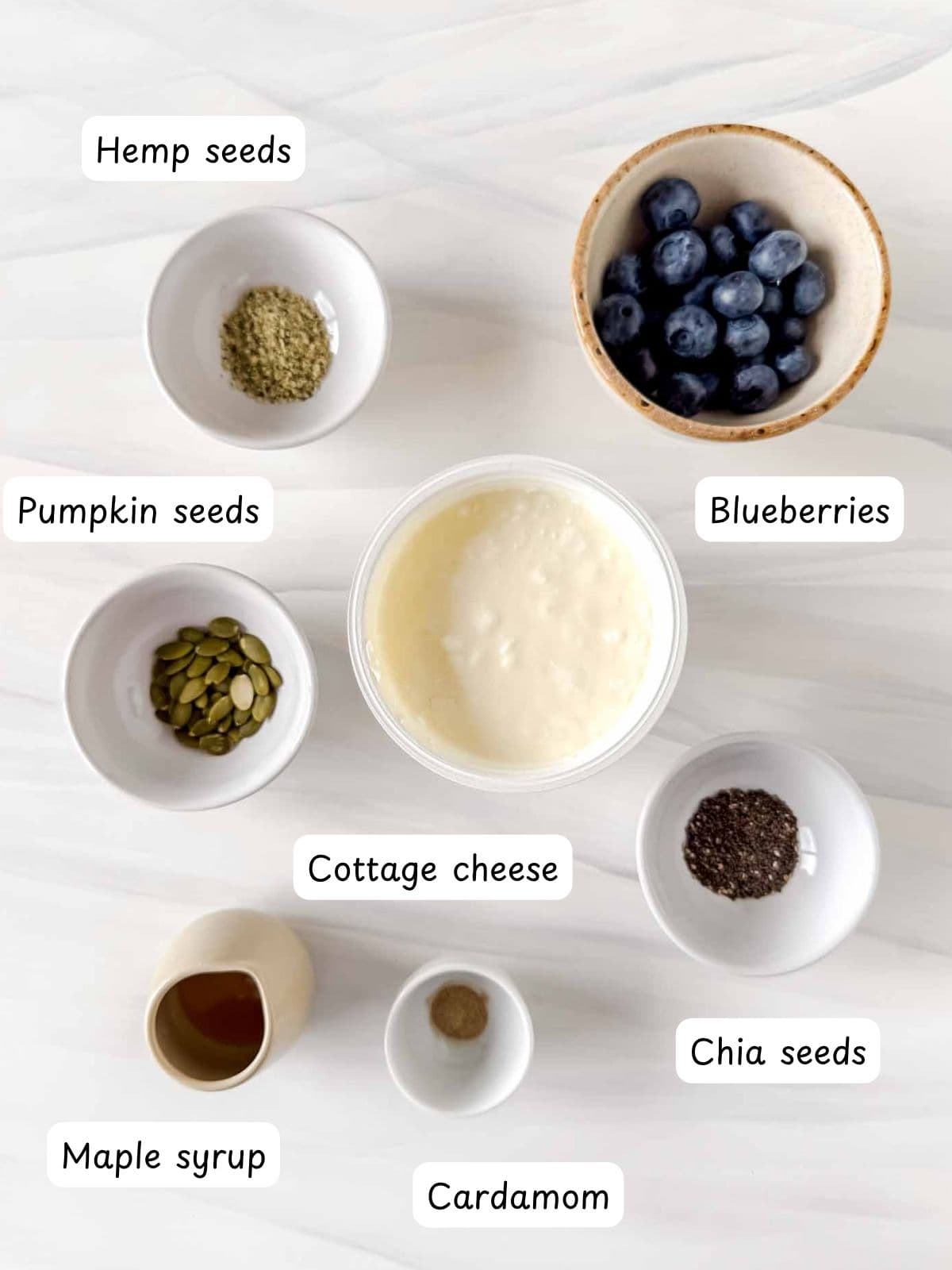 individually labelled cottage cheese, blueberries, hemp seeds, pumpkin seeds, maple syrup, cardamom and chia seeds.