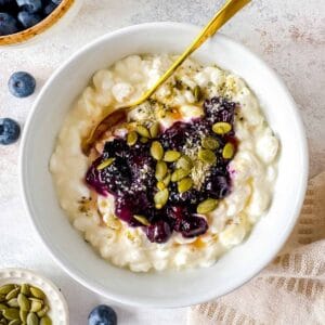 blueberry cottage bowl in a white bowl with a spoon topped with seeds.