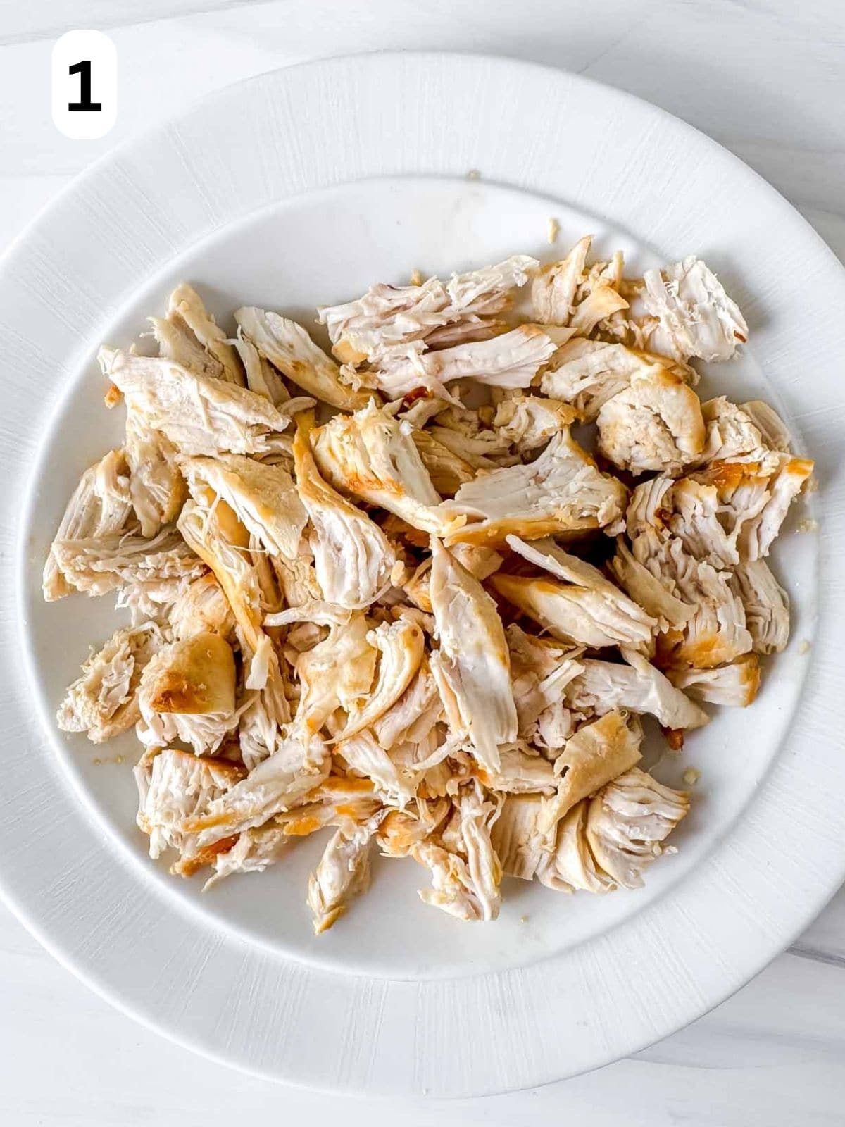 shredded chicken on a white plate labelled number one.