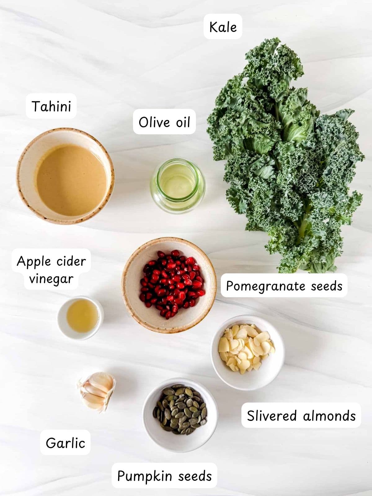 individually labelled kale, pomegranate seeds, tahini, olive oil, apple cider vinegar, garlic, pumpkin seeds and slivered almonds.