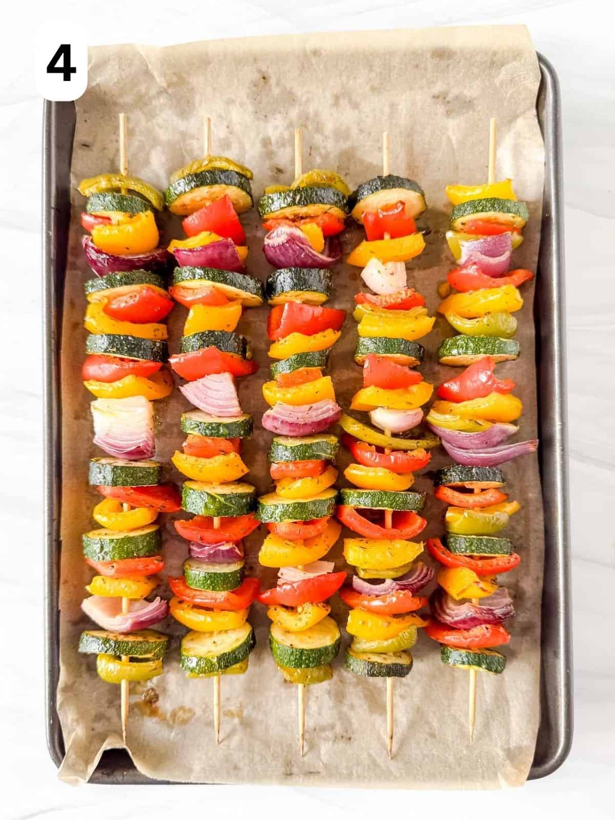 cooked oven veggie kabobs on a lined baking sheet labelled number four.